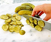 Close-up of man's hands cutting pickled cucumbers