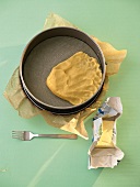 Short crust pastry being pressed into a spring form pan with baking paper in it