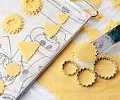 Close-up of different shaped biscuits being put on baking tray for baking