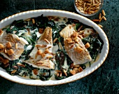 Close-up of saithe fillet with spinach and pine nuts in casserole