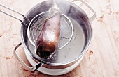 Eggplant being removed with skimmer from pot