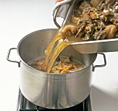 Pouring bone stock in pot, step 5