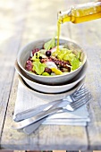 Olive oil being poured in squid salad in bowl