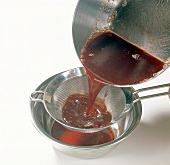 Mixture of jelly and jam being filtered with sieve in bowl, step 4