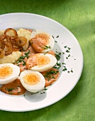Eggs in mustard and chilli sauce with potatoes and browned onions on plate