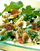 Close-up of pasta salad with salami, black olives and artichoke hearts in serving dish
