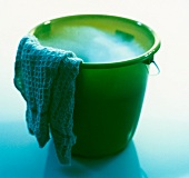 Close-up of green cleaning bucket with foam and cloth
