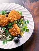 Close-up of fried turkey medallions with rice, grapes and parsley on plate
