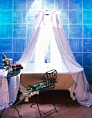 Bathtub with lace curtain and table with champagne