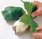Grape leaves being placed on partridge, step 2