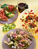Toast with ham and melon, band noodles with beef, lettuce and grapes on plate