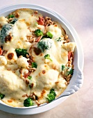 Close-up of cauliflower gratin with broccoli, onions, spelled and ham in bowl