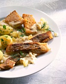 Close-up of coley fillet with apple celery sauce and potatoes on plate