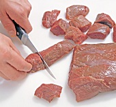 Close-up of meat being chopped for preparing venison stew, step 1
