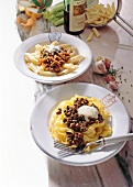 Fettuccine and penne pasta with wild duck ragout and cream on plates