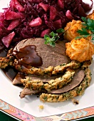 Close-up of leg of venison with mushroom crust, apple and red cabbage