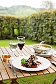 Laid table with oxtail on plate beside glass of wine in Ferme-Auberge du Bruel, France