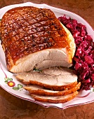 Sliced roast pork with apple, red cabbage and golden brown on plate