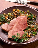 Close-up of shoulder of pork with herb lentils on plate