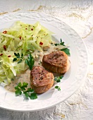 Close-up of white cabbage with pork medallions on plate