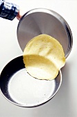 Pancake being glided smoothly on pan lid