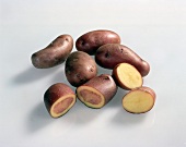 Close-up of whole and halved sweet potatoes on white background
