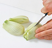Close-up of hands cutting fennel bulb into quarters, step 3