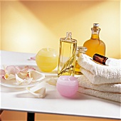 Massage oils, towels, candles and rose petals in a dish on white table