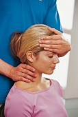 Relax-Massagen -Frau sitzt, Mann dahinter, drückt Hand auf Stirn,Hals
