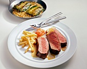 Sliced beef sirloin steak with French fries on plate
