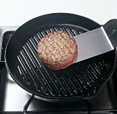 Close-up of frying hamburgers with spatula, step 5