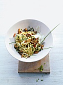 Tagliolini and pine nuts garnished with herb in white bowl