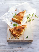 Two pieces of crispy herb flatbread on wooden board