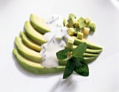 Avocado salad with yogurt-mint sauce on white background