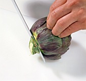 Close-up of hands cutting ends of artichoke, step 5