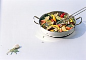 Ratatouille in casserole and rosemary on white background