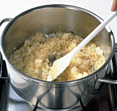 Rice, onions and oil being sauteed in pot. Step 2