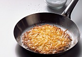 Hash browns in pan with sugar in glass