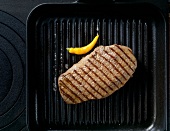 Beef steak with yellow hot peppers in broiler pan