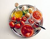 Metalltablett mit Zutaten für Tomatensauce: Öl, Knoblauch, Tomaten