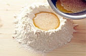 Close-up of egg beat being poured in flour for preparing pasta, step 2