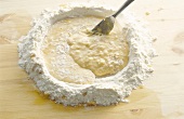 Close-up of egg beat and flour being mixed with fork for preparing pasta, step 3