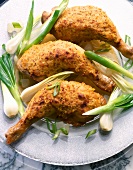 Close-up of chicken legs with mustard crust and green onions on plate