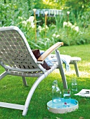 White deck chair made of aluminium and belt webbing standing in garden