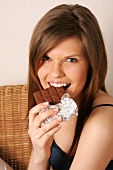Frau mit langen Haaren isst Tafel Schokolade