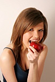 Portrait of woman with long hair biting into apple, smiling