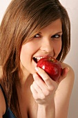 Portrait of woman with long hair biting into apple, smiling