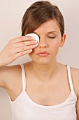 Close-up of pretty woman with brown hair cleaning her eyes with eye pad