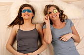 Magdalena and Charlotte women lying wearing eye masks seeing from her left eye, smiling