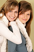 Portrait of two beautiful woman wearing sweater and scarf standing and smiling